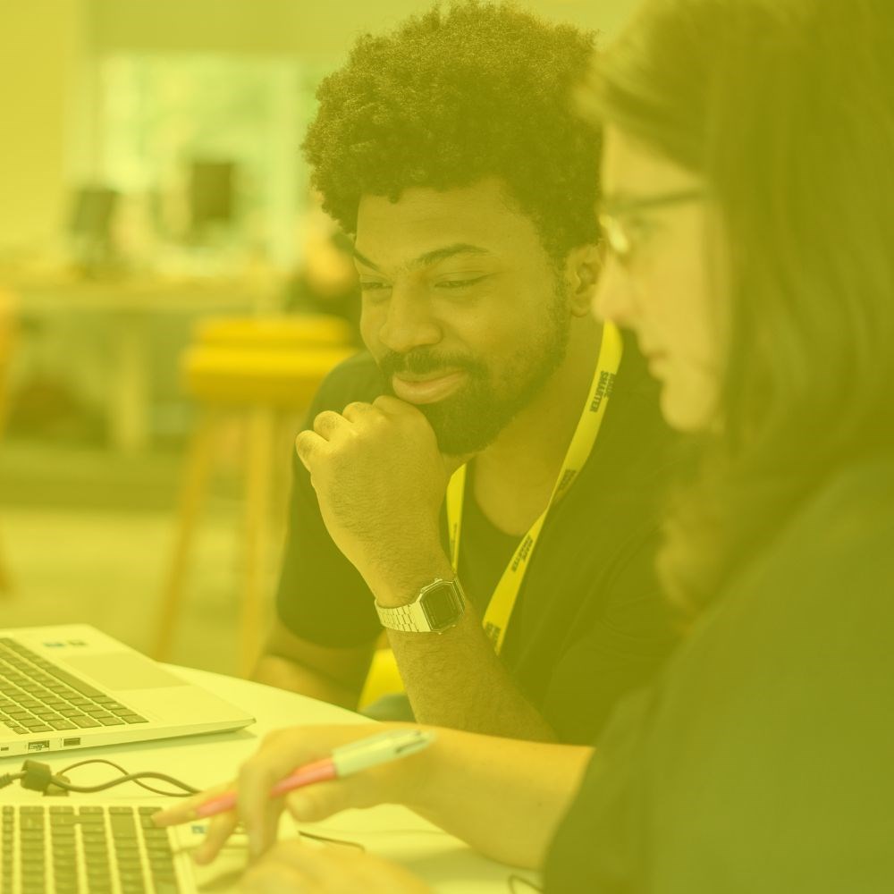 Two colleagues looking at a laptop together with a yellow tint 