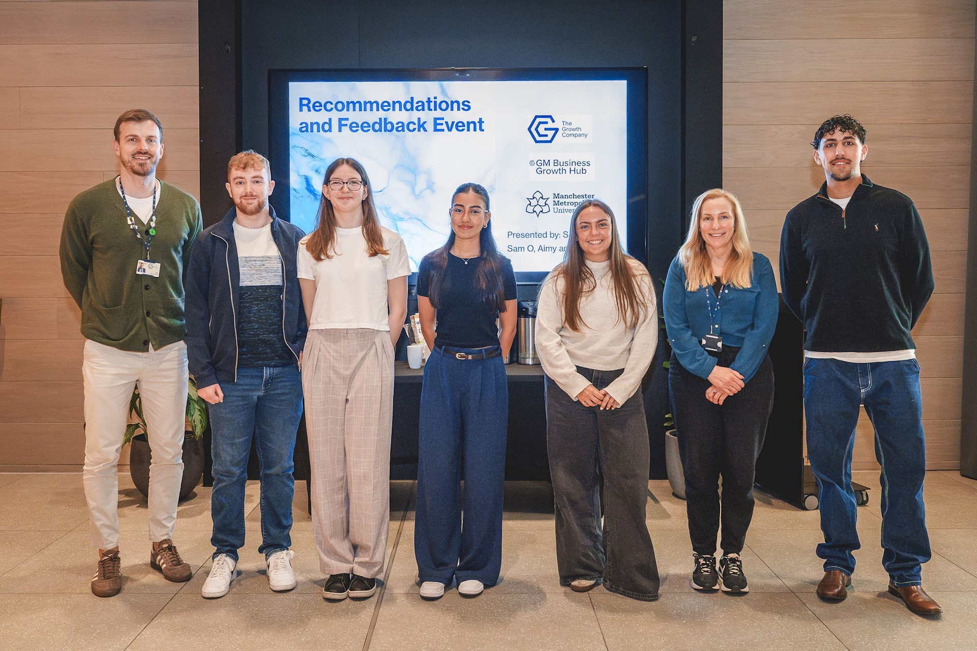 Group of 5 MMU students smiling with Matt and Adele after the recommendations and feedback event