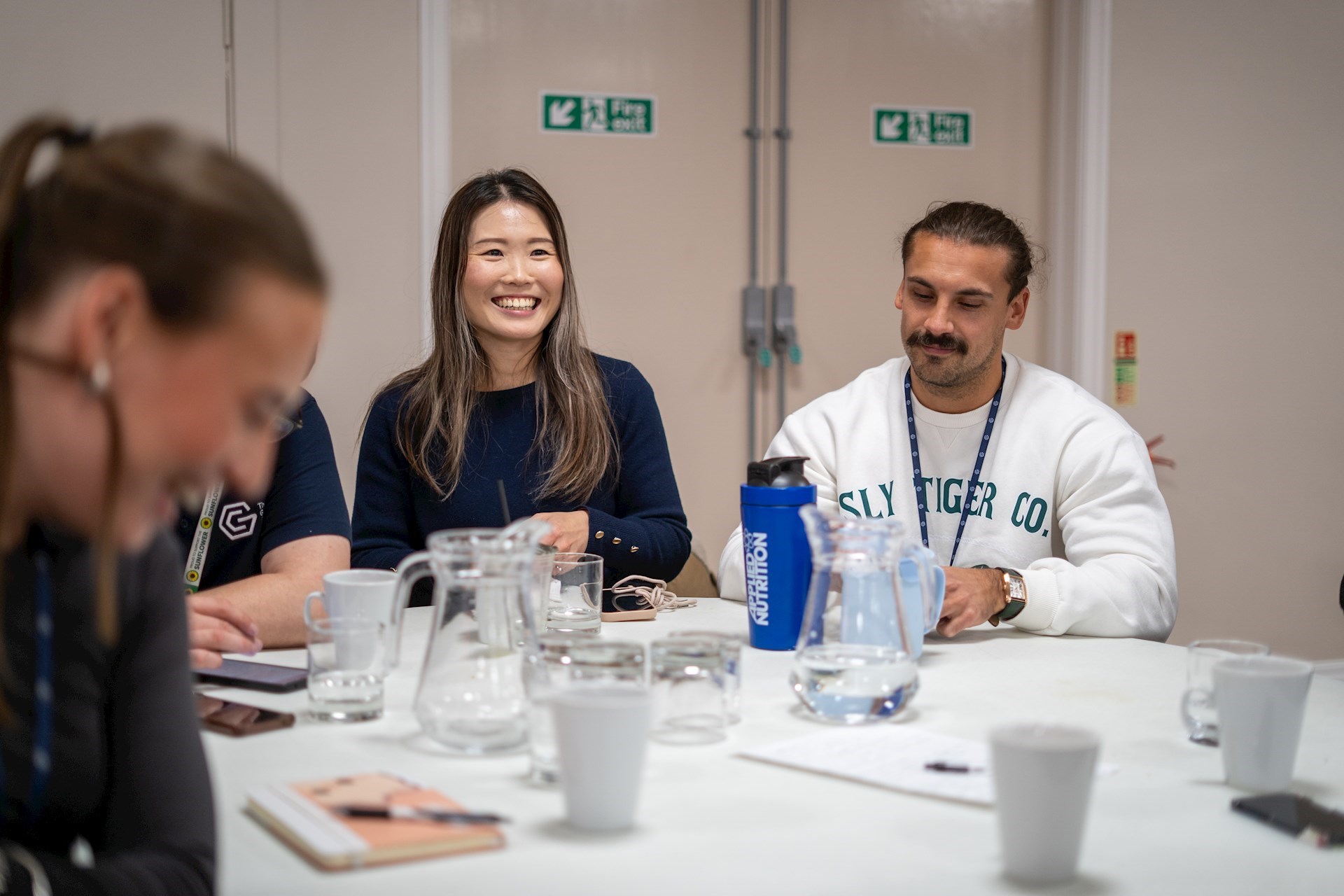 Colleagues sitting around a table with refreshments smiling and laughing