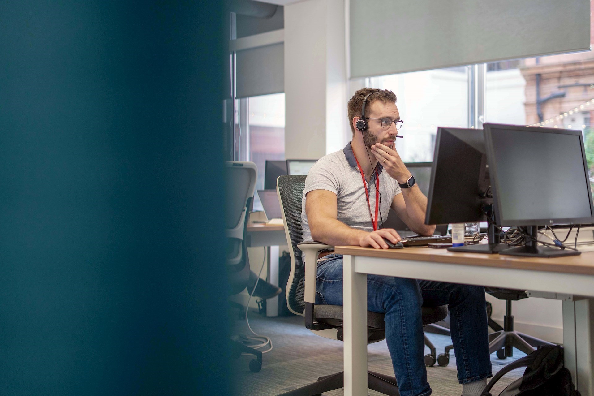 Colleague sitting as a desk working on a computer with a headset on