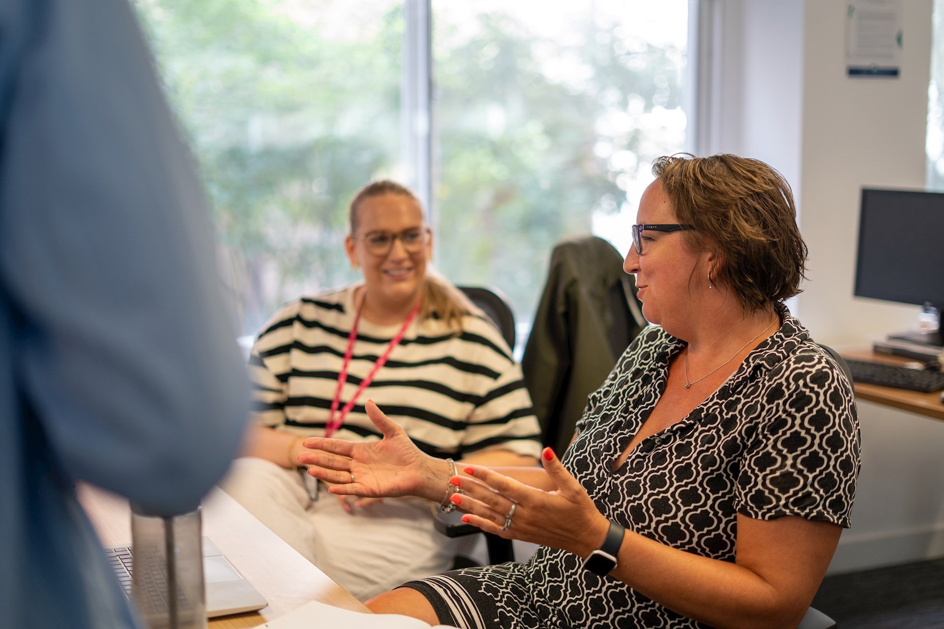 Two people sitting at a desk and having a conversation