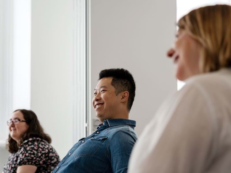 Image of 3 colleagues, smiling and participating in a meeting