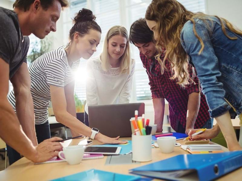 Image of people collaborating and looking at a laptop screen