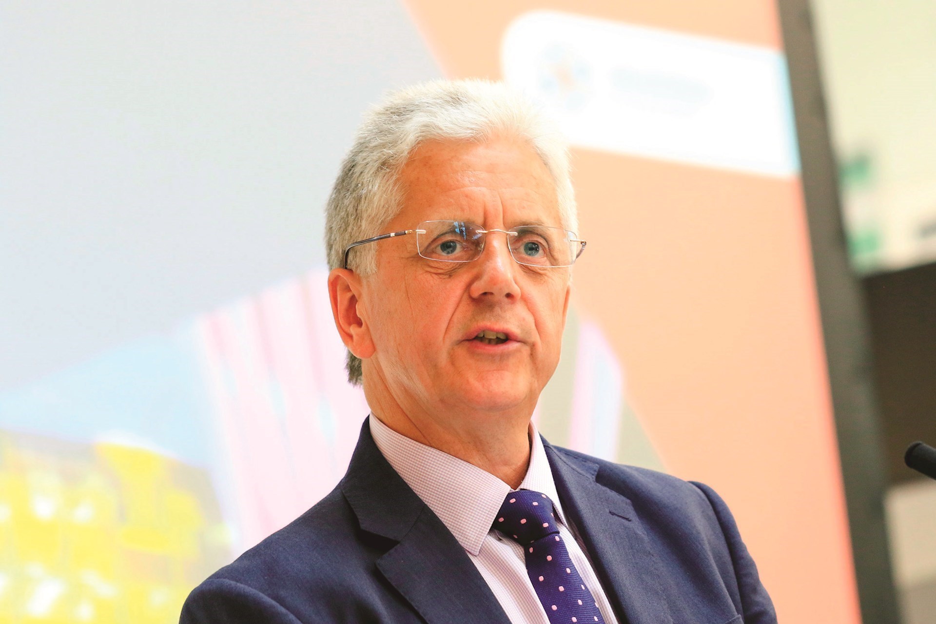 Mike Blackburn during a talk at an event wearing a dark suit with a blue tie