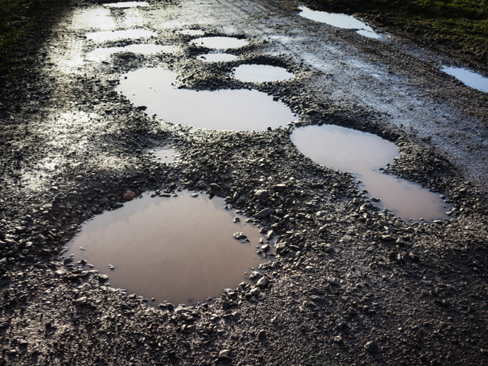Image of multiple pot holes in a road 